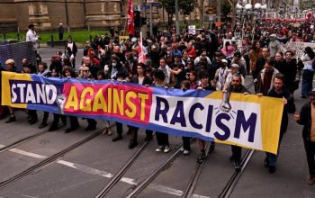 Orang-orang mengangkat spanduk dan plakat selama pawai protes anti-rasisme di Melbourne pada 13 September 2025 untuk melawan pengunjuk rasa anti-imigrasi dan anti-pemerintah dari demonstrasi Save Australia. (Photo by William WEST / AFP)