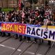 Orang-orang mengangkat spanduk dan plakat selama pawai protes anti-rasisme di Melbourne pada 13 September 2025 untuk melawan pengunjuk rasa anti-imigrasi dan anti-pemerintah dari demonstrasi Save Australia. (Photo by William WEST / AFP)